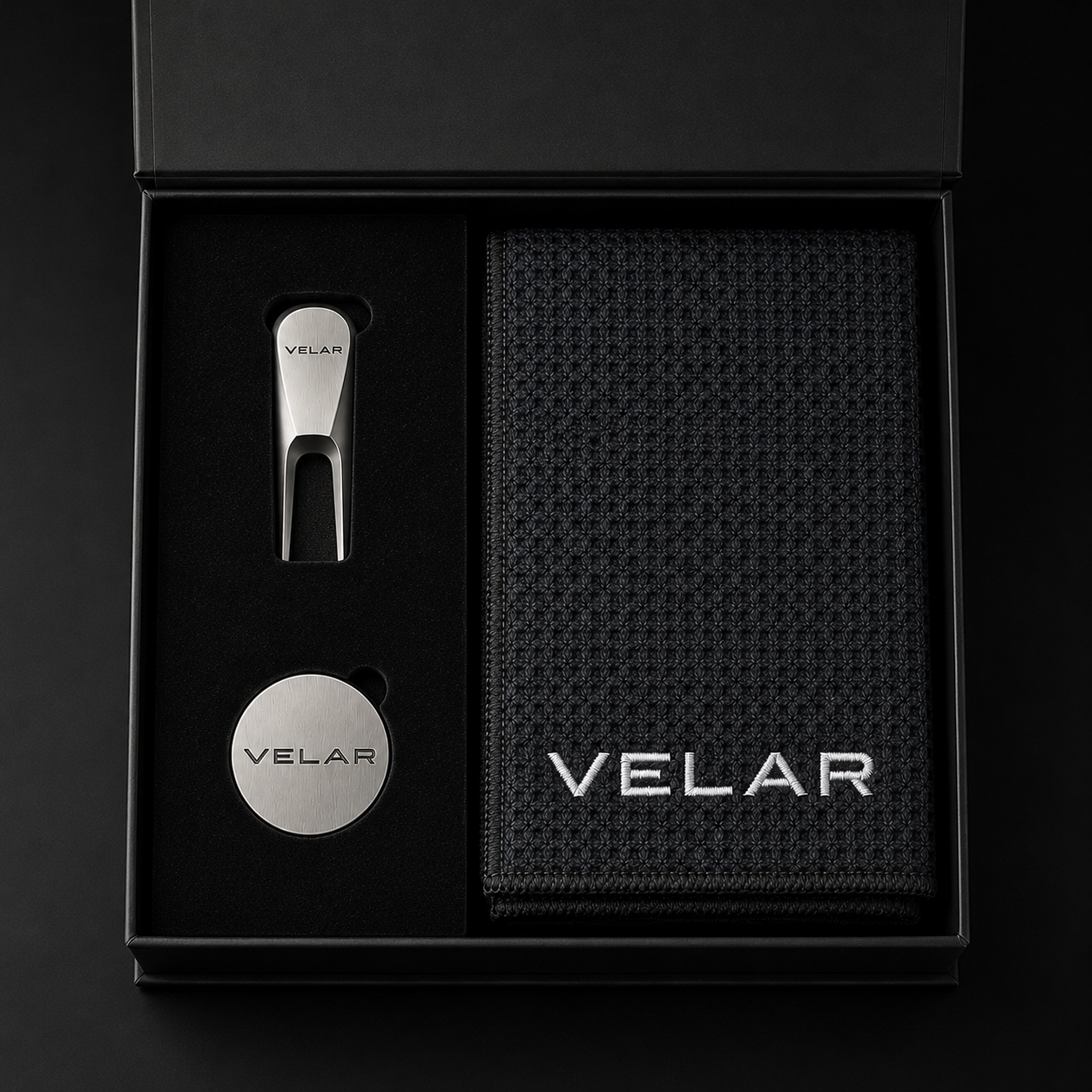 Overhead view of the VELAR gift box with the divot tool, ball marker and waffle-weave golf towel arranged inside